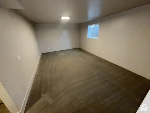 Spacious room featuring wood-finish flooring, neutral wall tones, a flush-mount ceiling light, and a window