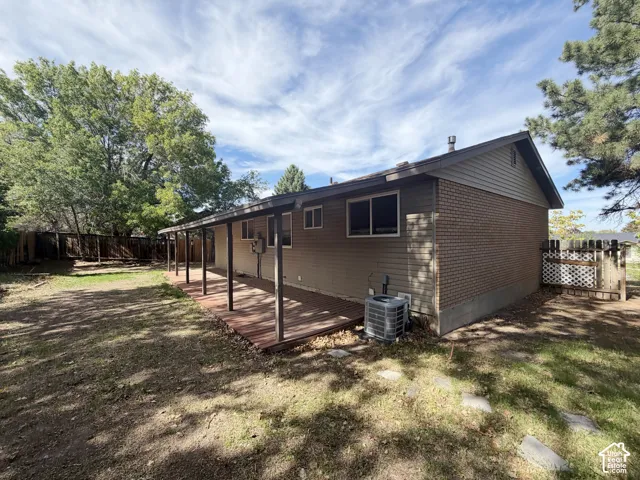 Expansive backyard featuring a wood deck, mature trees, and privacy fencing