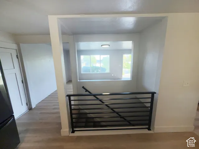 Wood-finish flooring throughout, modern black metal railing, interior window, white trim details, and recessed lighting