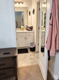 Vanity area with white cabinetry, wall-mounted light fixture, and mirror