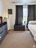 Wall-to-wall carpeting and a window with dark drapery