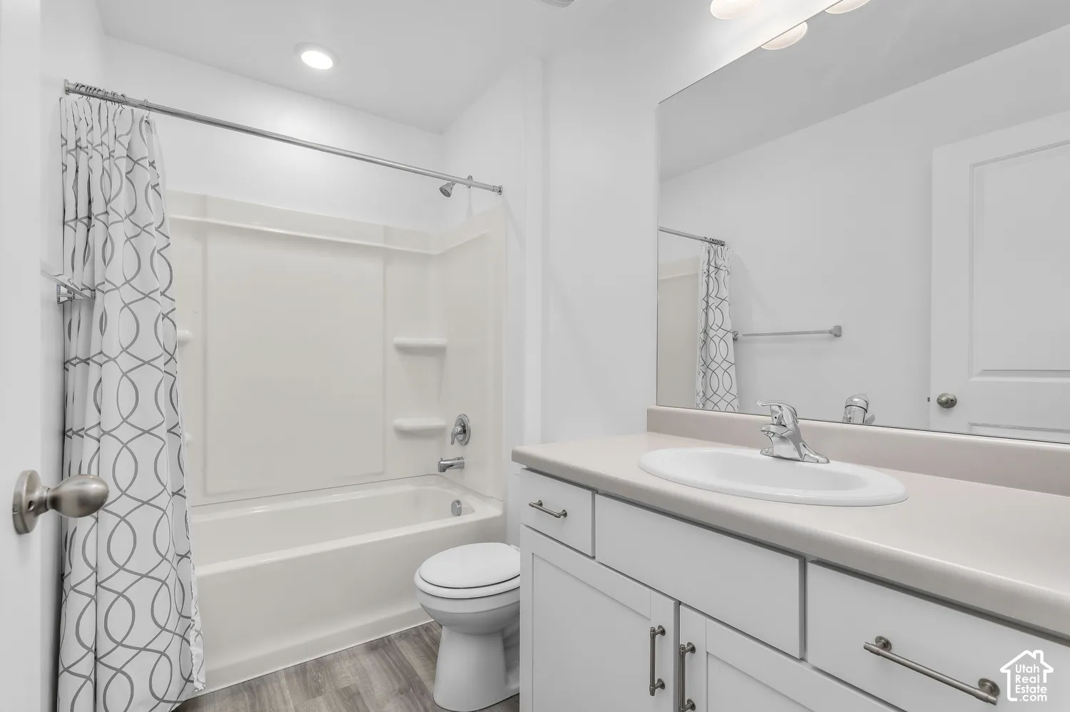 Bathroom featuring a white vanity cabinet with an integrated sink, brushed-nickel hardware, a full-width mirror, and a tub-shower combination with recessed shelving