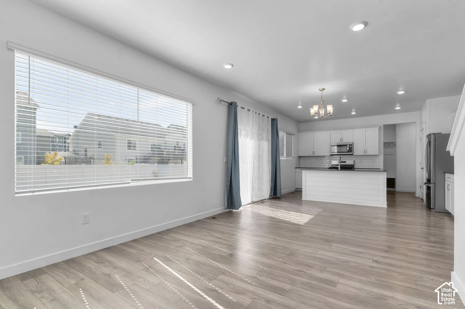 Open-concept interior featuring wood-finish flooring, recessed lighting, white cabinetry, a kitchen island with shiplap detailing, and sliding glass doors