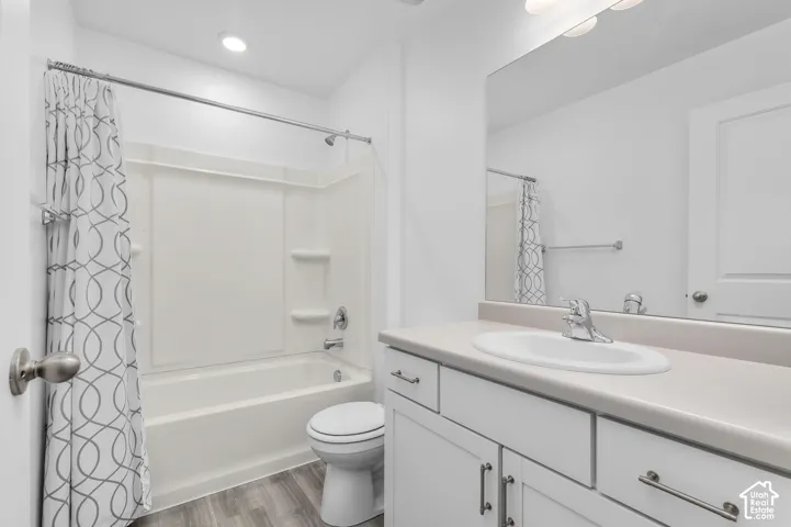 Bathroom featuring a white vanity cabinet with an integrated sink, brushed-nickel hardware, a full-width mirror, and a tub-shower combination with recessed shelving