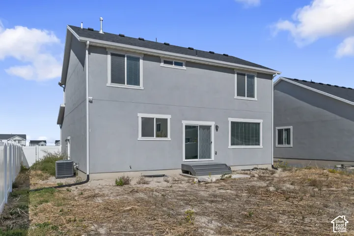 Two-story exterior featuring smooth-finish stucco siding, a gabled roof with asphalt shingles, sliding glass doors, white vinyl fencing, and an exterior air conditioning unit