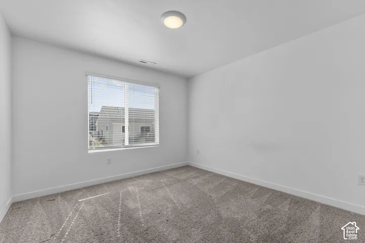Neutral-toned wall-to-wall carpeting, crisp white walls, and a recessed ceiling light fixture, accented by a window with integrated blinds