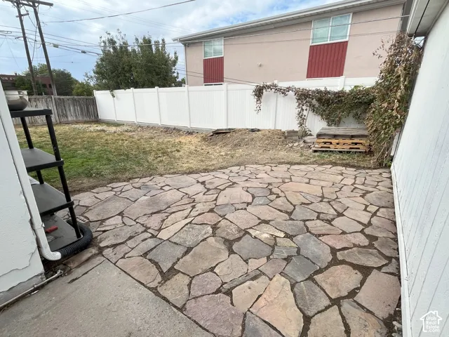 Flagstone patio featuring an irregular stone pattern enclosed by a vinyl privacy fence