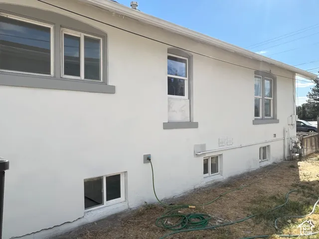 Stucco exterior with contrasting trim, multi-pane sliding windows, and lower-level foundation windows