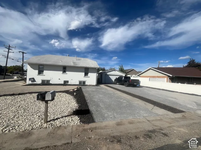 White exterior finish, detached garage, gravel driveway, and decorative rock landscaping