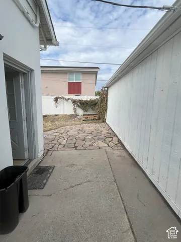 Exterior area featuring concrete flatwork, flagstone hardscaping, and white vinyl privacy fencing