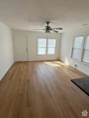Wood-finish flooring, multi-pane windows with horizontal blinds, and a central ceiling fan with integrated lighting