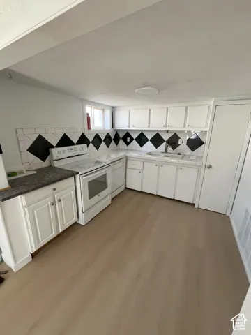 Kitchen featuring white cabinetry, wood-finish flooring, a tiled backsplash with diamond-pattern detailing, a built-in dishwasher, and a white range