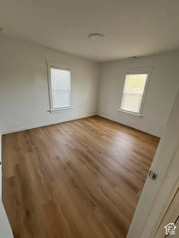 Wood-finish flooring, neutral wall tones, and dual windows with fitted blinds