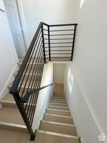 Staircase featuring black metal horizontal railings and light-toned treads
