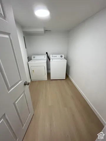 Laundry area featuring wood-finish flooring, white walls, and a recessed ceiling light fixture
