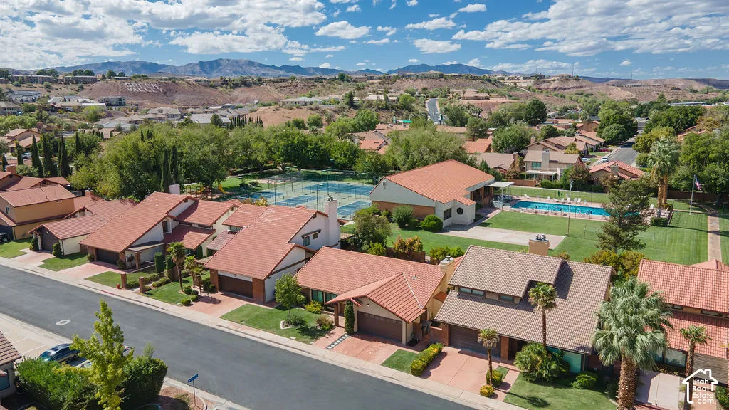 Residential street with tile-roofed homes, mature landscaping, and mountain backdrop
