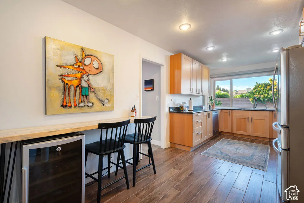 Kitchen featuring a built-in wine refrigerator, wood-finish flooring, recessed lighting, wood cabinetry, and a large window