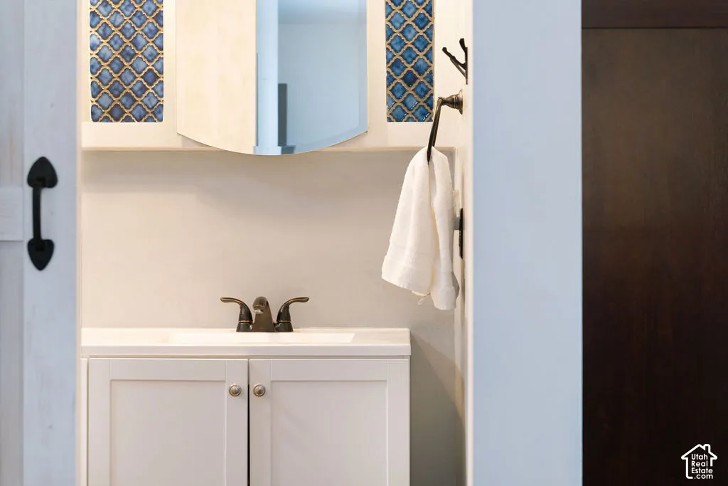 White vanity with shaker-style cabinet doors, integrated sink, and bronze-finish faucet