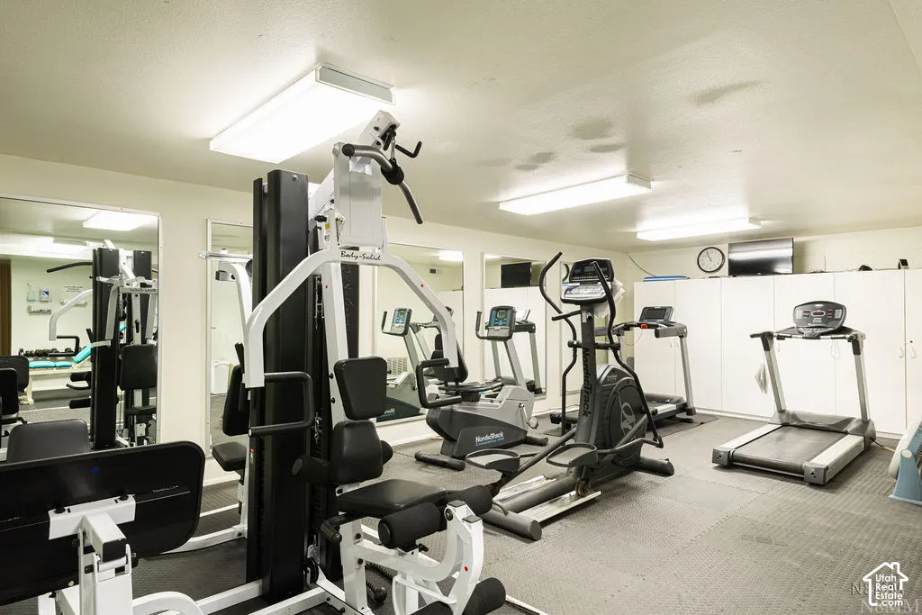 Dedicated fitness area featuring extensive built-in storage, full-wall mirrors, and recessed lighting