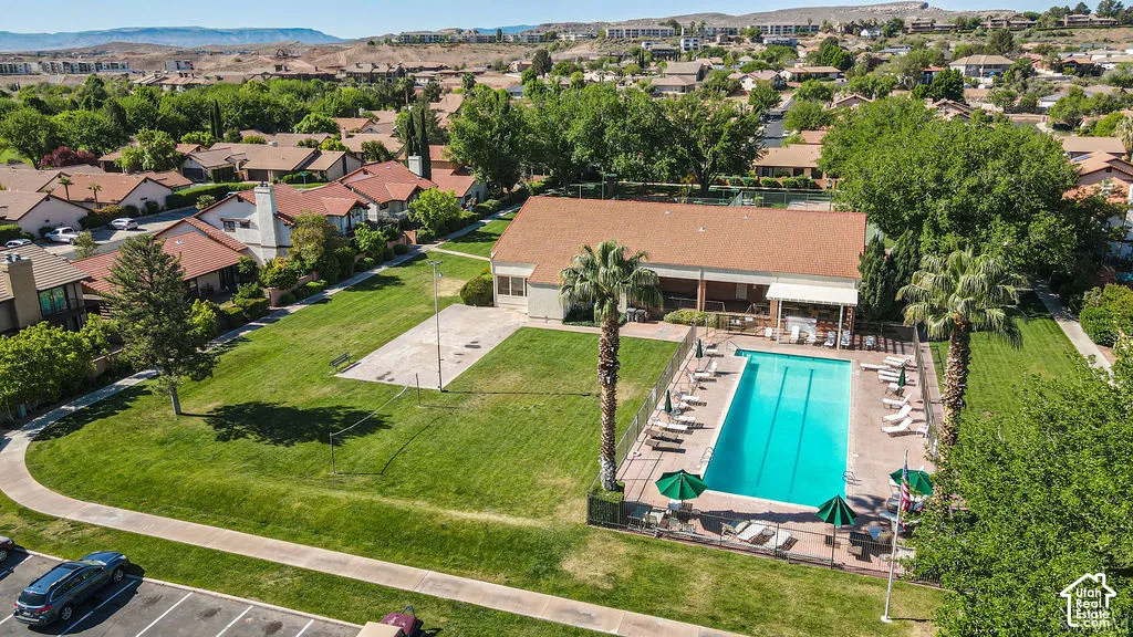 Community swimming pool with surrounding patio, adjacent lawn area, and nearby building structure