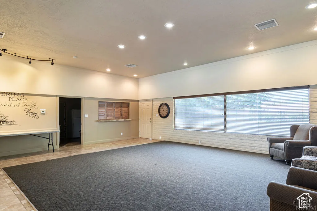 Recessed lighting, track lighting, neutral wall tones, large window with blinds, and white brick wall accent