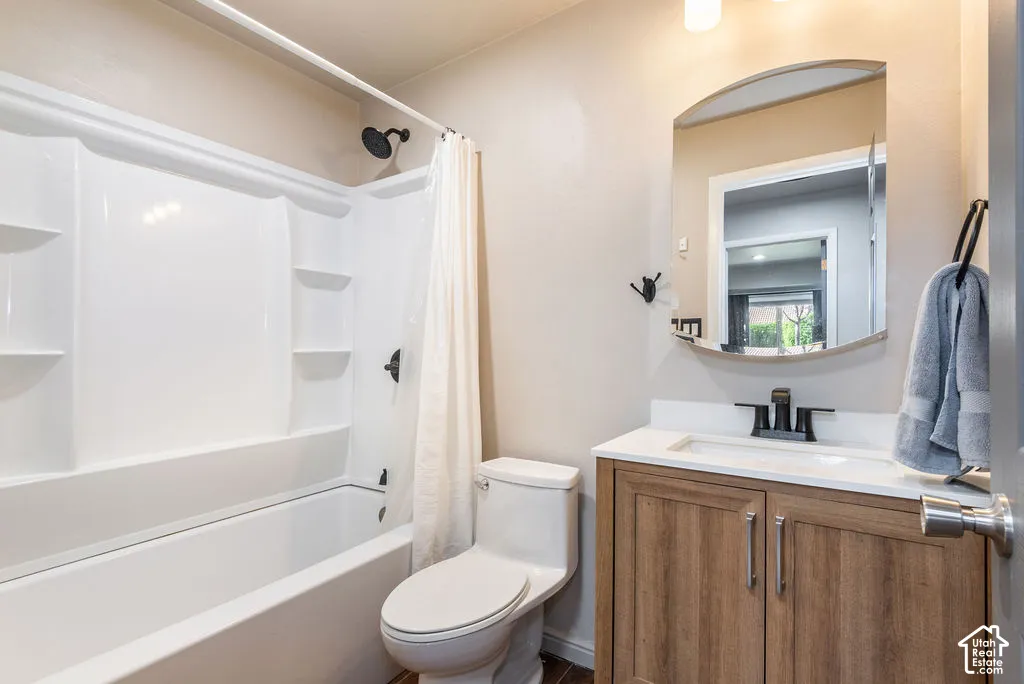 Bathroom featuring a white tub and shower combination, wood-finish vanity with a white countertop, recessed sink, and an arched mirror
