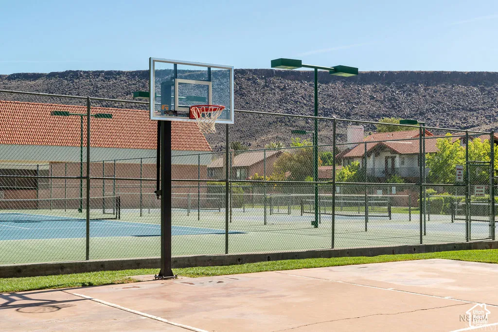 Basketball court with a clear backboard and red net, adjacent to fenced tennis courts