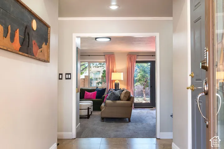 Entryway with tile flooring, a contemporary overhead light fixture, and an open doorway leading to a carpeted living space