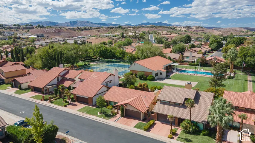 Residential street with tile-roofed homes, mature landscaping, and mountain backdrop