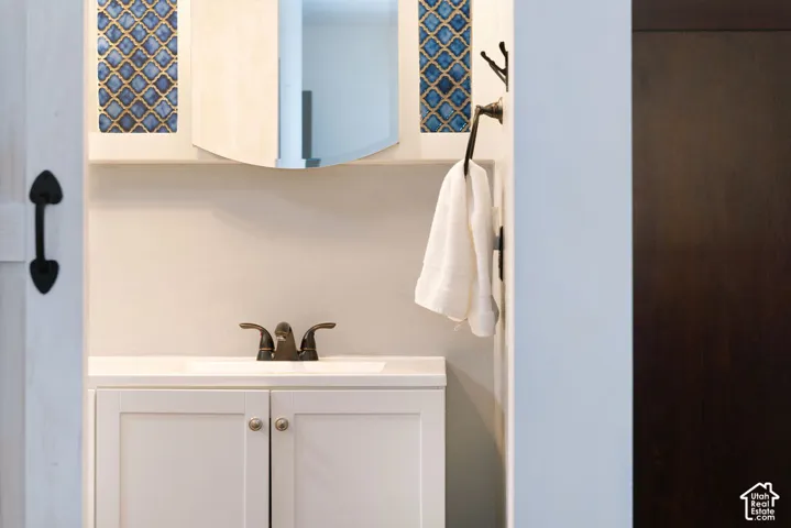 White vanity with shaker-style cabinet doors, integrated sink, and bronze-finish faucet