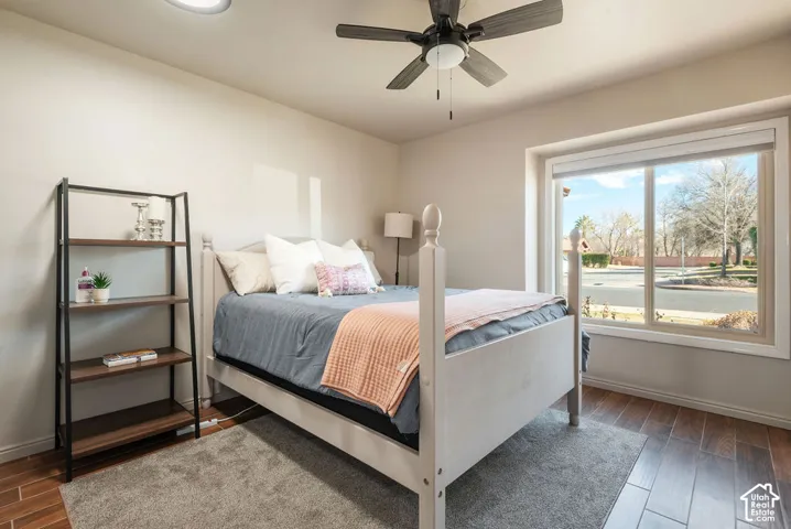 Wood-finish flooring, ceiling fan with integrated lighting, recessed lighting, and a large window with roller shades