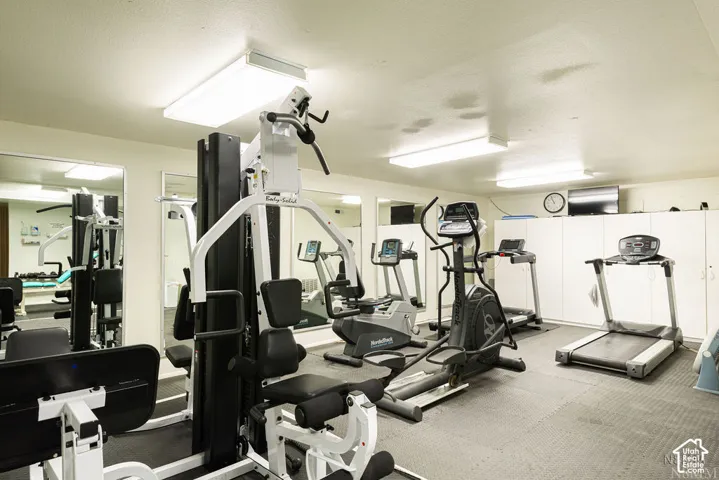 Dedicated fitness area featuring extensive built-in storage, full-wall mirrors, and recessed lighting