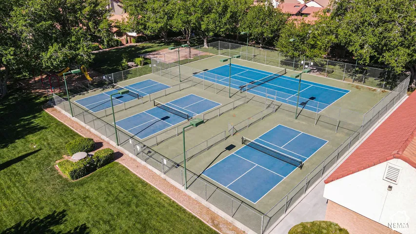 Multiple hard courts featuring blue playing surfaces, perimeter fencing, and overhead lighting