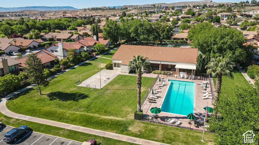 Community swimming pool with surrounding patio, adjacent lawn area, and nearby building structure