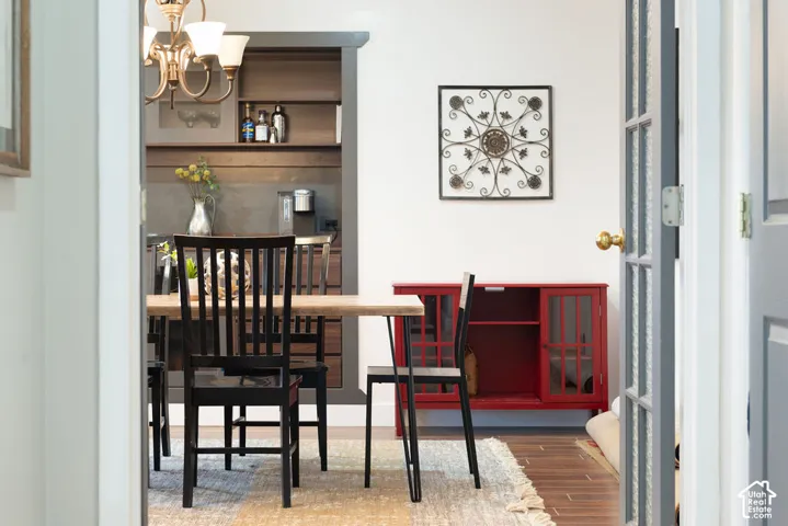 Dining area featuring a bronze chandelier, wood-finish flooring, and a built-in shelving unit