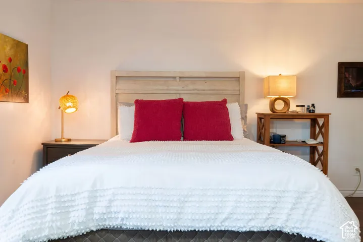 Light-toned wooden headboard, light-toned wood flooring, and white painted walls