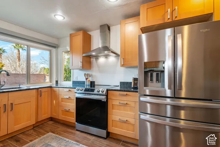 Kitchen featuring wood-finish cabinetry, black countertops, stainless steel appliances, and wood-finish flooring