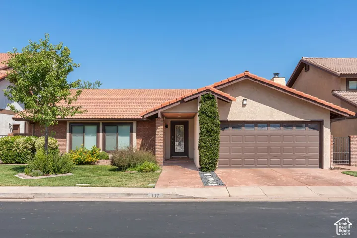 Terracotta tile roofing, brick facade, stamped concrete driveway, and attached two-car garage