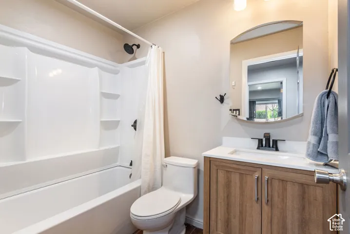 Bathroom featuring a white tub and shower combination, wood-finish vanity with a white countertop, recessed sink, and an arched mirror