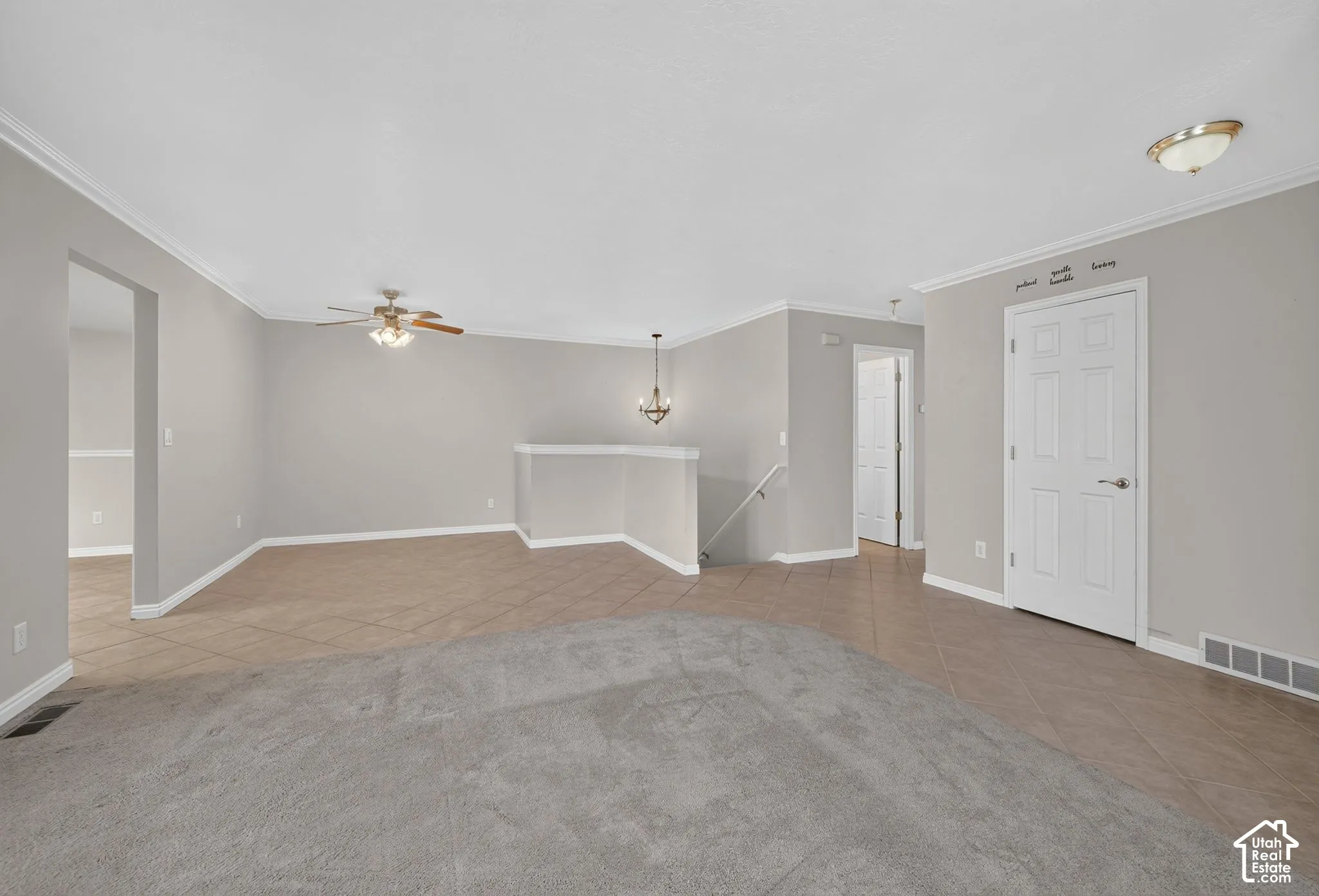 Neutral-toned interior featuring ceramic tile flooring, neutral wall-to-wall carpeting, a ceiling fan with integrated lighting, a multi-arm chandelier, and a six-panel interior door