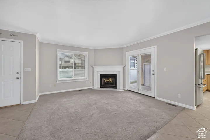 Living area featuring a corner fireplace with a white mantel, dual-pane window, and glass-paneled exterior doors with access to an outdoor patio