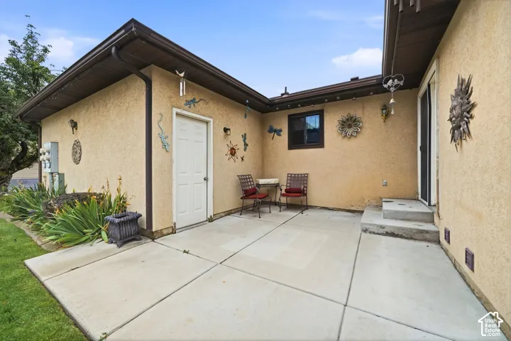Concrete patio featuring a stucco exterior, single-entry door, and two-step concrete stoop