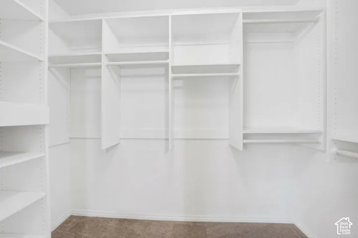 Main bedroom Walk-in closet featuring white custom built-in shelving, multiple hanging rods, and adjustable storage partitions