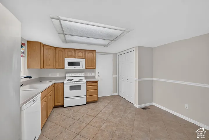 Kitchen featuring oak cabinetry, white appliances, built-in microwave, tile flooring, and a flush-mount ceiling fixture