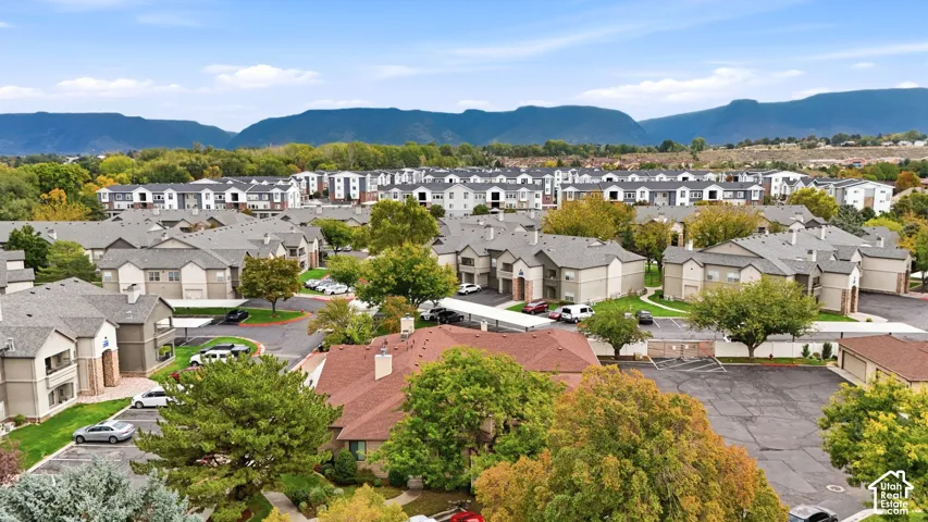 Multi-family residential complex featuring asphalt shingle roofing, paved surface parking, covered carport structures, and expansive mountain range scenery