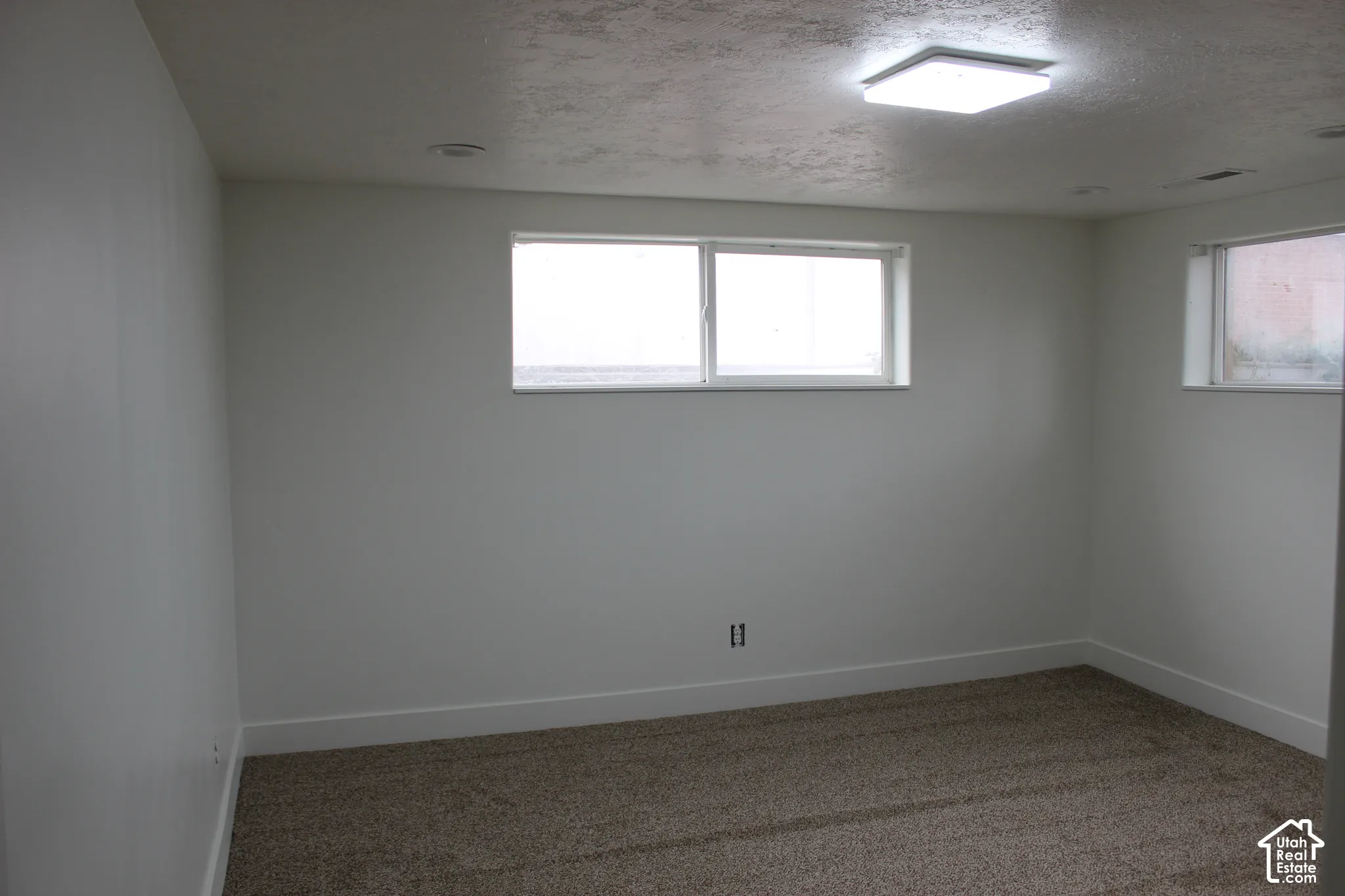 Neutral-toned interior space featuring wall-to-wall carpeting, white painted walls, recessed ceiling lighting, and two horizontal sliding windows