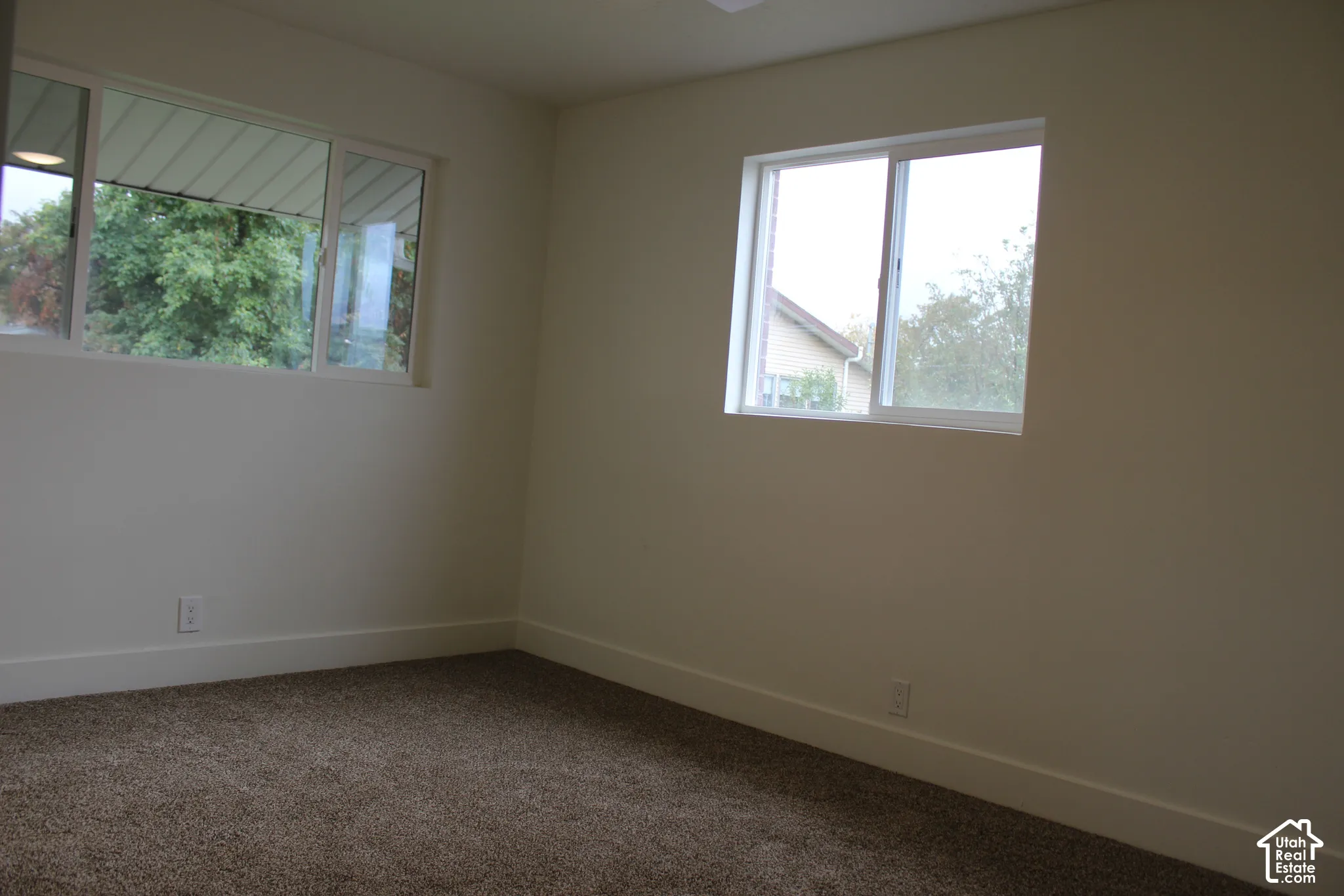 Interior space featuring neutral wall paint, carpeted flooring, and two dual-pane sliding windows