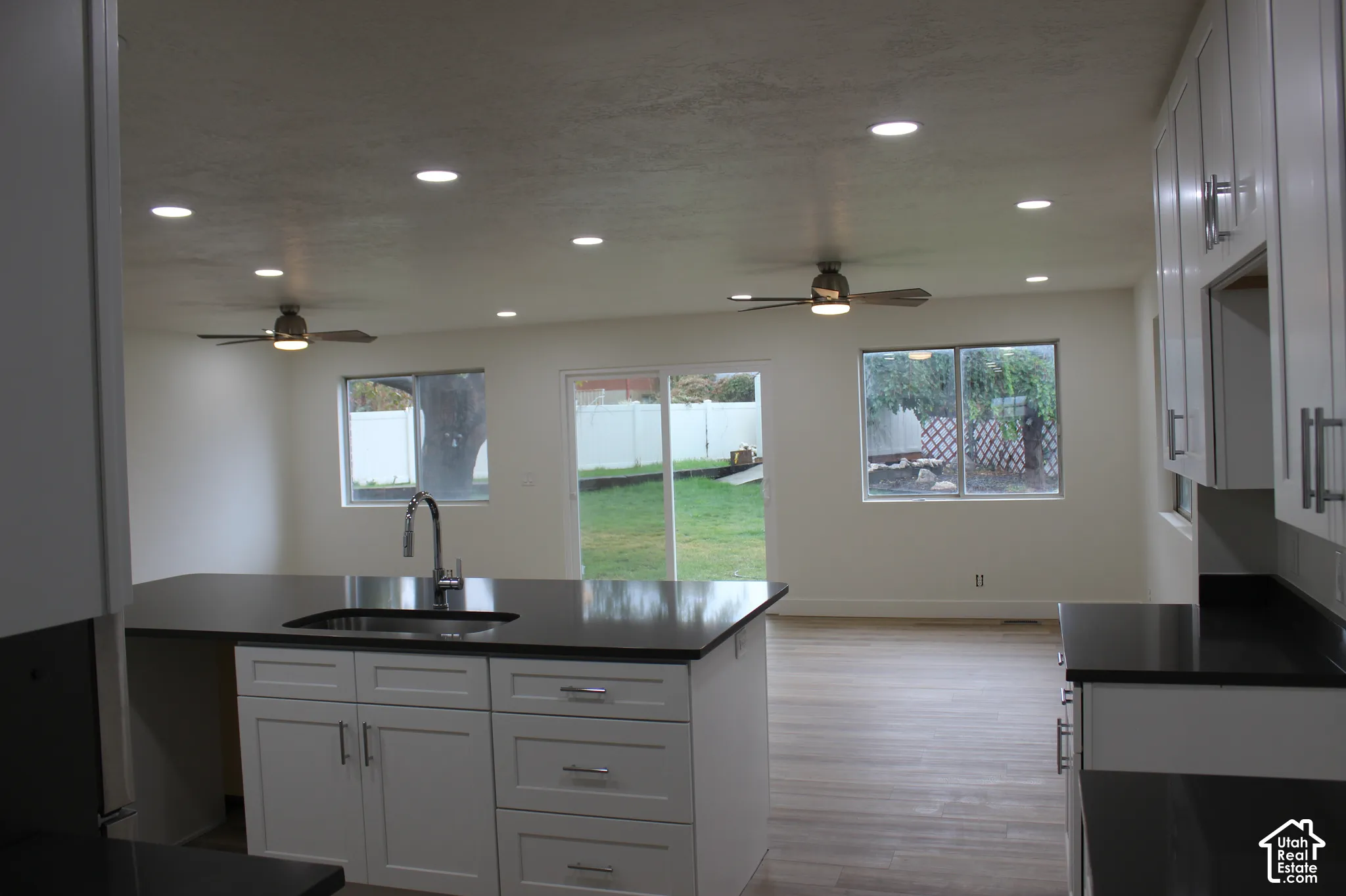 Kitchen featuring white shaker-style cabinetry, dark solid-surface countertops, wood-finish flooring, recessed lighting, and dual ceiling fans