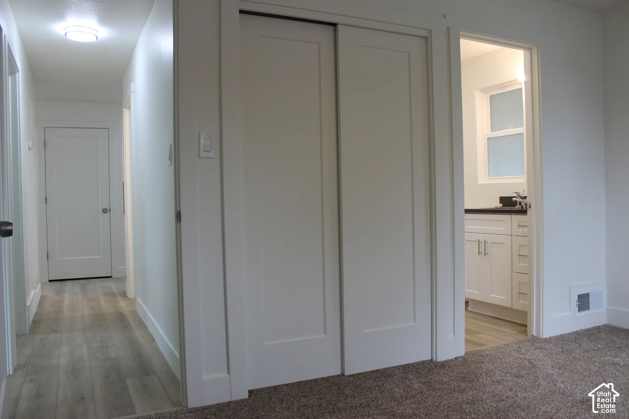 Neutral-toned interior featuring wood-finish flooring, shaker-style closet doors, solid-core interior doors, and a vanity with integrated storage