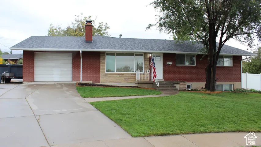 Single-story residence featuring a brick and stone exterior, attached one-car garage, concrete driveway, and pitched asphalt shingle roof